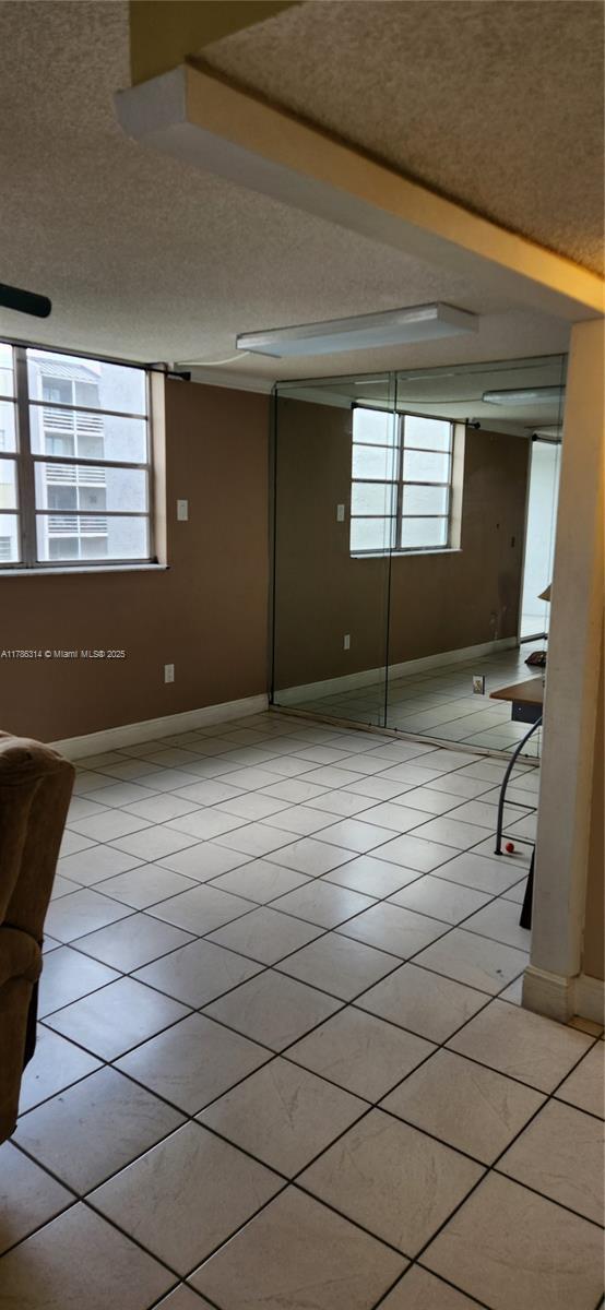 empty room featuring baseboards, a textured ceiling, and light tile patterned floors