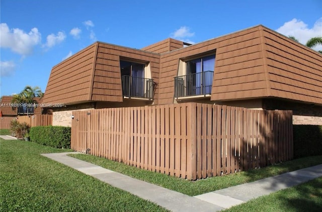 2572 Lakeview Ct, Cooper City, FL 33026 - view of side of home with fence, a yard, mansard roof, and a balcony