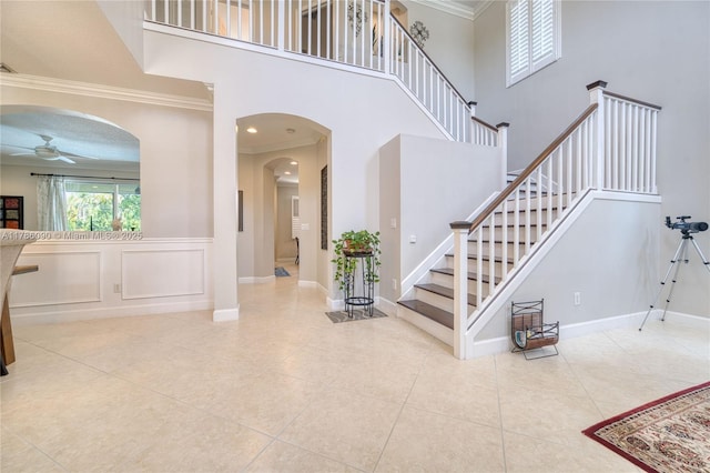 1454 Newhaven Point Ln, West Palm Beach, FL 33411 - tiled entryway with arched walkways, ceiling fan, crown molding, a high ceiling, and stairs
