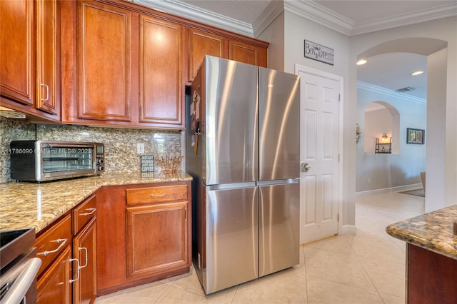 1454 Newhaven Point Ln, West Palm Beach, FL 33411 - kitchen with freestanding refrigerator, arched walkways, ornamental molding, tasteful backsplash, and light stone countertops