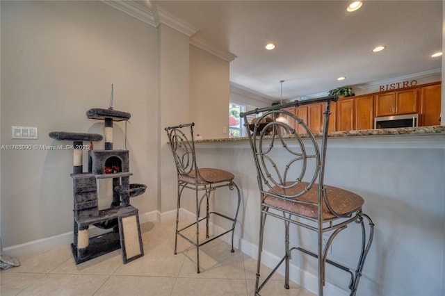 1454 Newhaven Point Ln, West Palm Beach, FL 33411 - kitchen featuring ornamental molding, stainless steel microwave, brown cabinetry, recessed lighting, and light stone counters