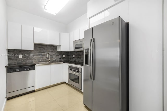6365 Collins Ave Unit 805, Miami Beach, FL 33141 - kitchen with tasteful backsplash, appliances with stainless steel finishes, dark countertops, a sink, and white cabinetry