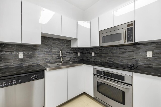 6365 Collins Ave Unit 805, Miami Beach, FL 33141 - kitchen with white cabinetry, appliances with stainless steel finishes, decorative backsplash, and a sink