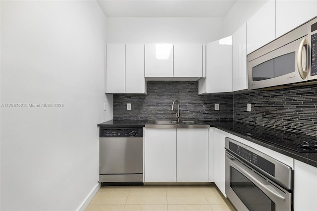 6365 Collins Ave Unit 805, Miami Beach, FL 33141 - kitchen featuring stainless steel appliances, stainless steel counters, backsplash, a sink, and white cabinetry