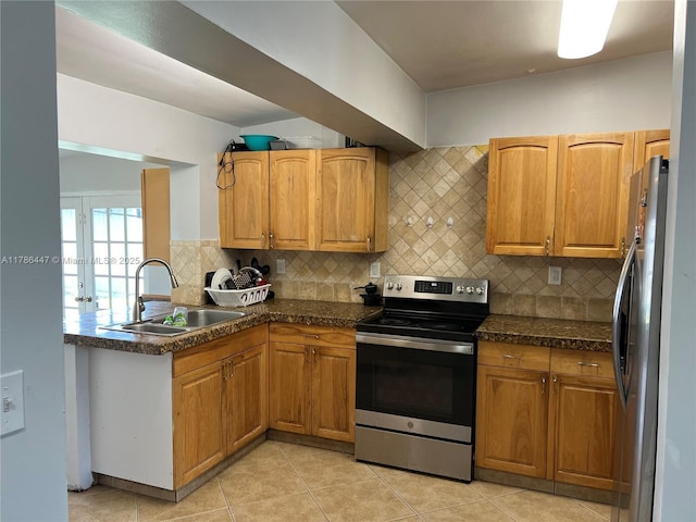 kitchen featuring backsplash, dark countertops, stainless steel appliances, and a sink