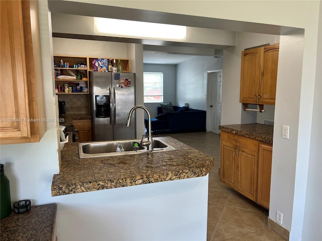 kitchen featuring a peninsula, a sink, stainless steel fridge with ice dispenser, tile countertops, and light tile patterned floors