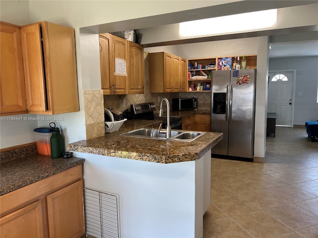 kitchen with a peninsula, stainless steel fridge with ice dispenser, dark countertops, and a sink