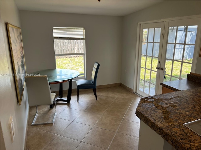 dining area featuring tile patterned flooring, baseboards, a healthy amount of sunlight, and french doors