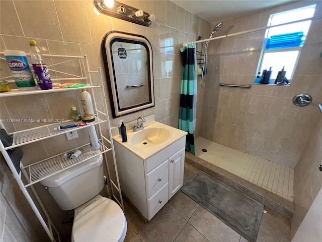full bath featuring a tile shower, tile patterned flooring, toilet, vanity, and tile walls