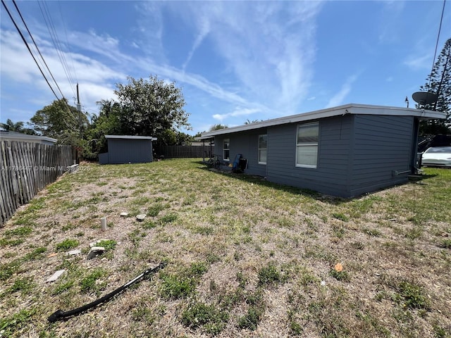 view of yard with fence, an outbuilding, and a shed