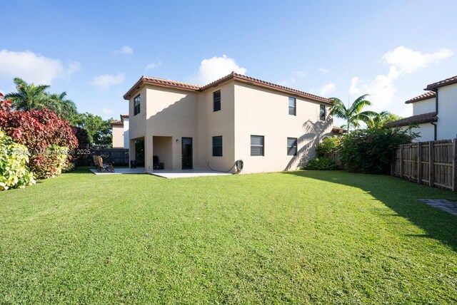 102 NE 23rd Ter, Homestead, FL 33033 - rear view of house featuring a fenced backyard, a yard, stucco siding, a tile roof, and a patio