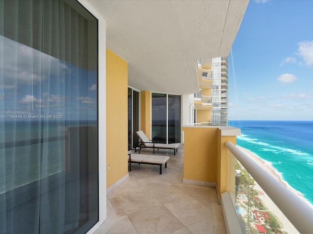 balcony featuring a view of the beach and a water view