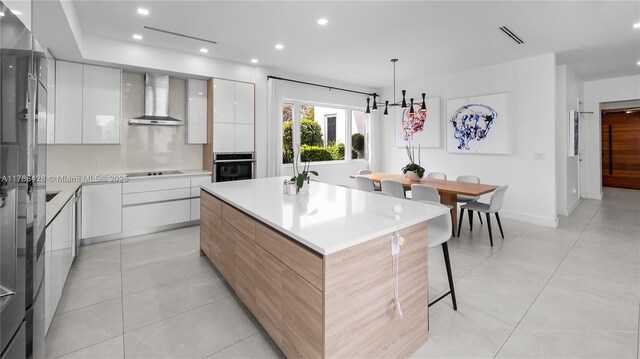 10603 NE 11th Ave, Miami Shores, FL 33138 - kitchen featuring modern cabinets, wall chimney range hood, stainless steel oven, a kitchen island, and white cabinetry