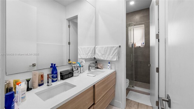 10603 NE 11th Ave, Miami Shores, FL 33138 - bathroom featuring a stall shower, double vanity, toilet, and wood finished floors
