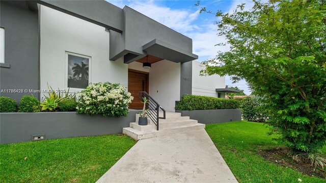 10603 NE 11th Ave, Miami Shores, FL 33138 - view of exterior entry featuring a yard and stucco siding