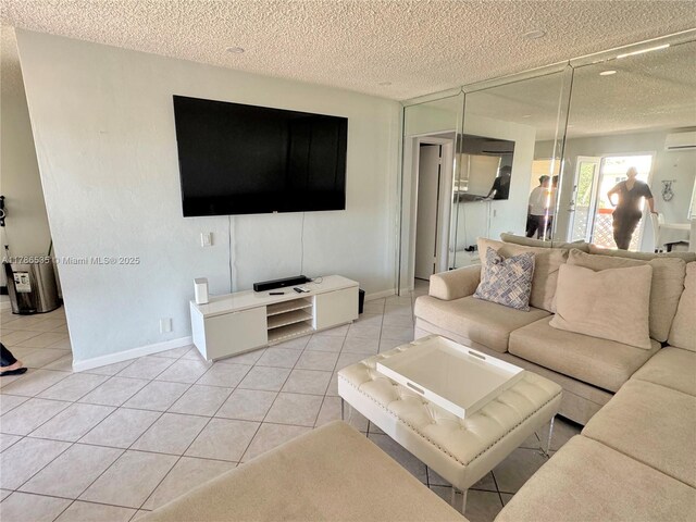living area with baseboards, a textured ceiling, a wall mounted AC, and light tile patterned floors
