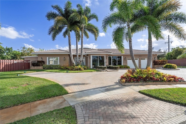 single story home featuring fence, a garage, a front yard, stucco siding, and decorative driveway