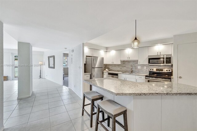 3000 Holiday Dr Unit 306, Fort Lauderdale, FL 33316 - kitchen featuring stainless steel appliances, tasteful backsplash, light tile patterned floors, a breakfast bar, and white cabinets