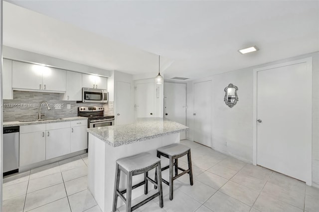 3000 Holiday Dr Unit 306, Fort Lauderdale, FL 33316 - kitchen with appliances with stainless steel finishes, a sink, tasteful backsplash, a breakfast bar area, and light tile patterned floors