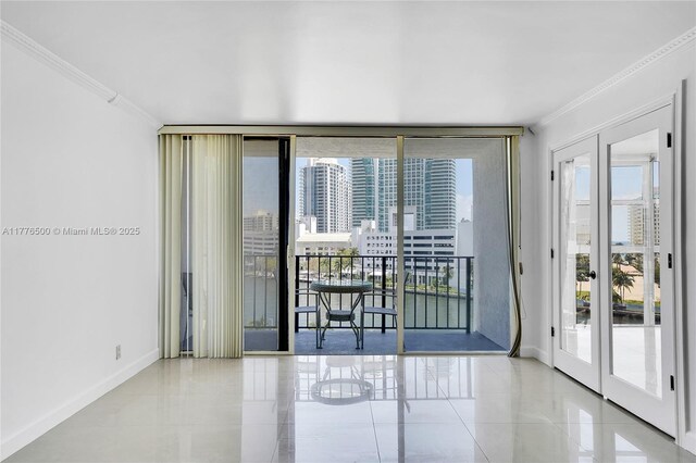 unfurnished room with french doors, ornamental molding, tile patterned floors, healthy amount of natural light, and baseboards