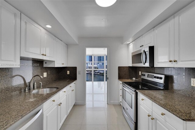 kitchen featuring appliances with stainless steel finishes, white cabinets, and dark stone countertops