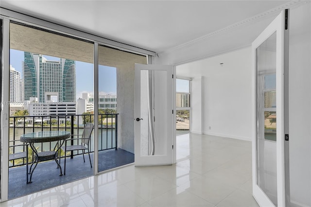 spare room with tile patterned floors, a city view, baseboards, ornamental molding, and a water view