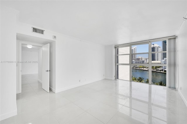 unfurnished room featuring baseboards, a water view, a city view, and light tile patterned floors