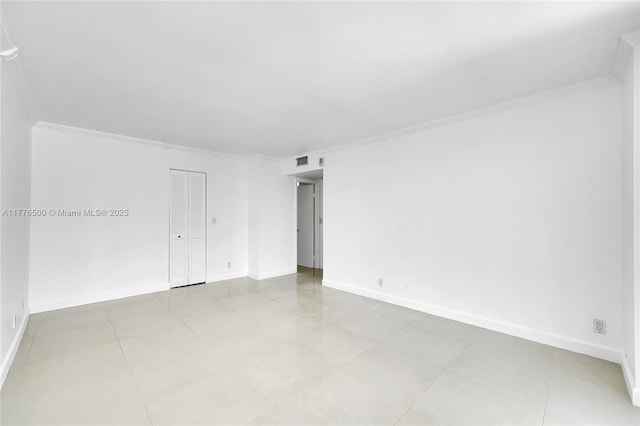 empty room with ornamental molding, baseboards, and tile patterned floors