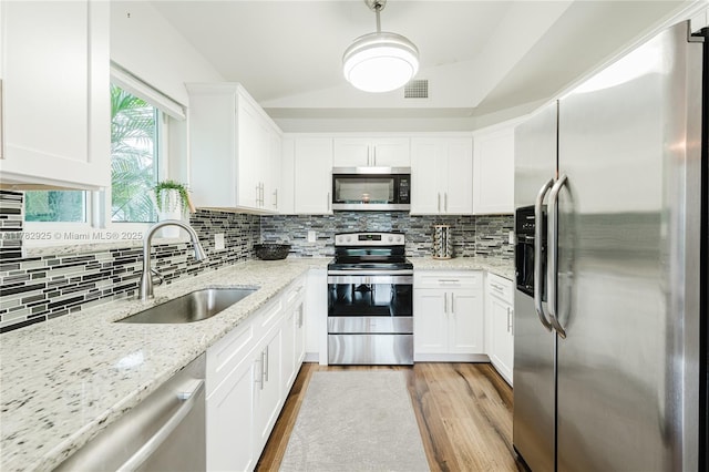 kitchen with light wood finished floors, visible vents, a sink, tasteful backsplash, and appliances with stainless steel finishes