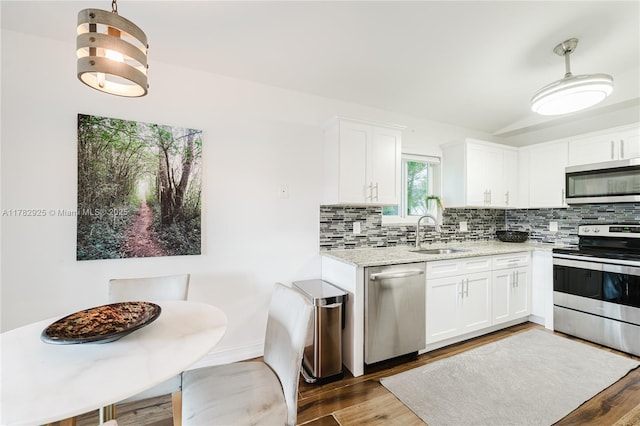 kitchen with light stone counters, a sink, decorative backsplash, white cabinetry, and appliances with stainless steel finishes