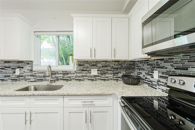 kitchen featuring tasteful backsplash, a sink, stainless steel appliances, white cabinetry, and light stone countertops