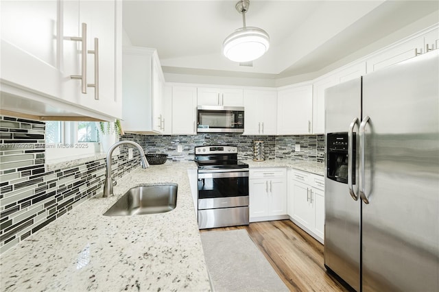 kitchen with tasteful backsplash, white cabinetry, stainless steel appliances, and a sink