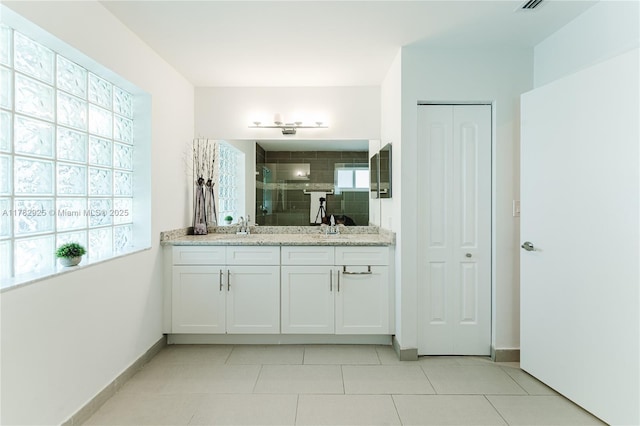 bathroom with a shower stall, tile patterned floors, double vanity, a sink, and baseboards