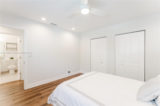 bedroom with multiple closets, wood finished floors, visible vents, a ceiling fan, and baseboards
