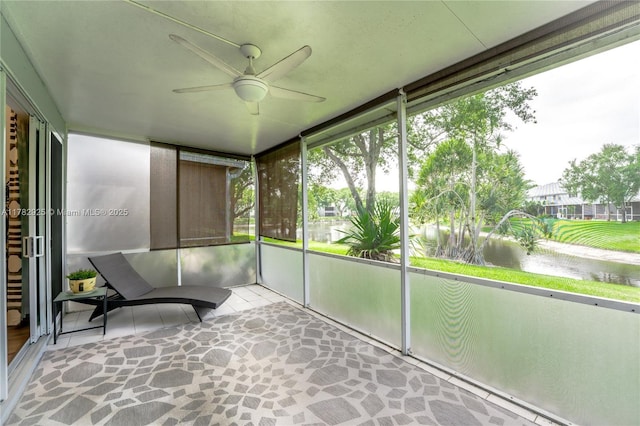 sunroom / solarium with a ceiling fan and a water view