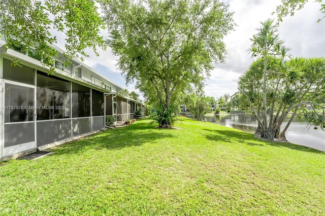 view of yard with a sunroom and a water view