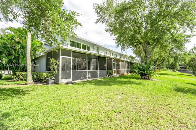 rear view of house with a lawn and a sunroom