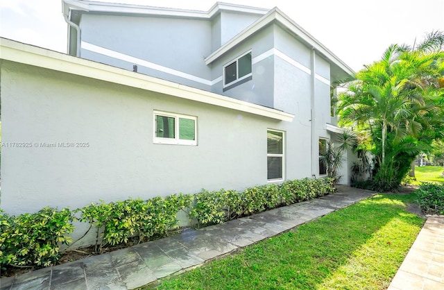 view of side of home featuring a lawn and stucco siding
