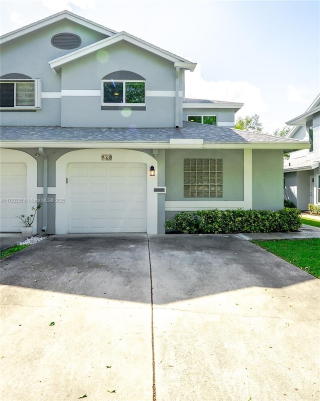 view of front facade with cooling unit, concrete driveway, an attached garage, stucco siding, and roof with shingles