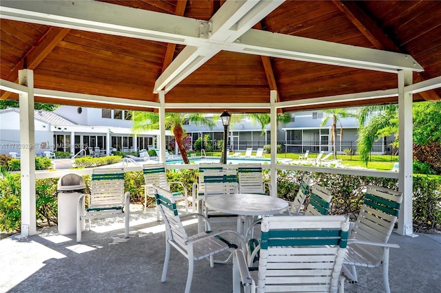view of patio / terrace with a gazebo, outdoor dining area, a community pool, and fence
