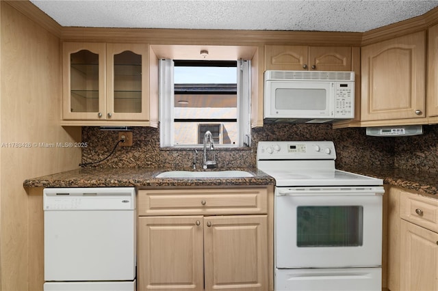 kitchen featuring light brown cabinets, a sink, decorative backsplash, white appliances, and glass insert cabinets