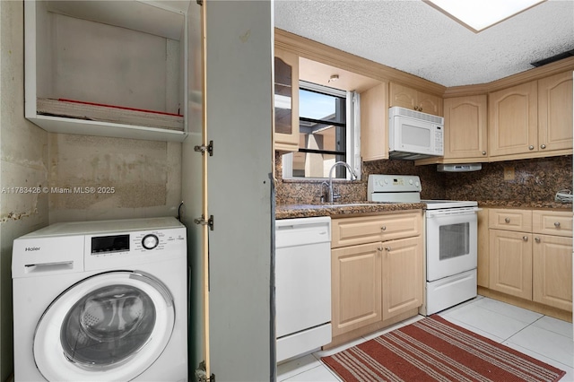 interior space featuring a sink, a textured ceiling, light tile patterned flooring, washer / clothes dryer, and laundry area