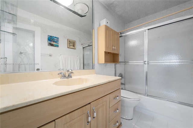 full bath with tile walls, vanity, enclosed tub / shower combo, and toilet