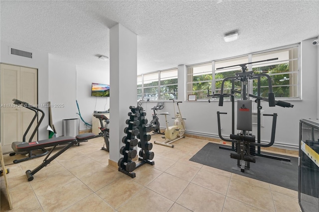 gym with baseboards, tile patterned flooring, a textured ceiling, and visible vents