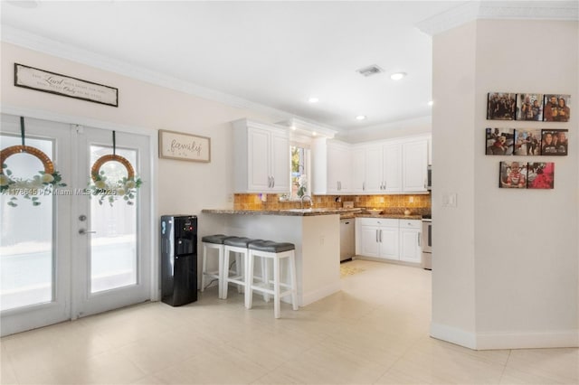 kitchen featuring a peninsula, tasteful backsplash, dishwashing machine, and white cabinets