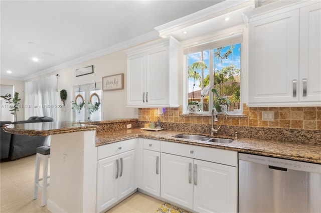 kitchen with a peninsula, a sink, stone counters, white cabinetry, and dishwasher