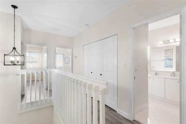 hallway featuring baseboards, a sink, and a notable chandelier