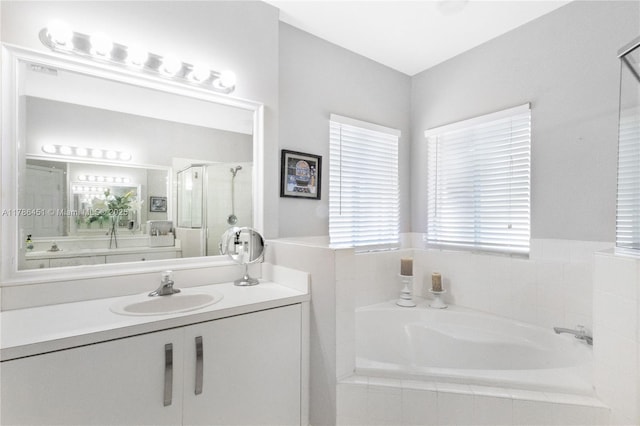 bathroom featuring a bath, a shower stall, and vanity