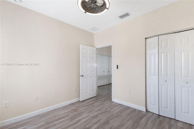 unfurnished bedroom featuring a closet, light wood-type flooring, visible vents, and baseboards