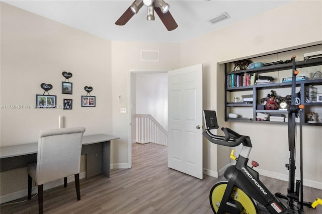 interior space with visible vents, baseboards, wood finished floors, and ceiling fan